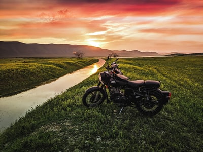 Black motorcycle at sunset on the green grass
